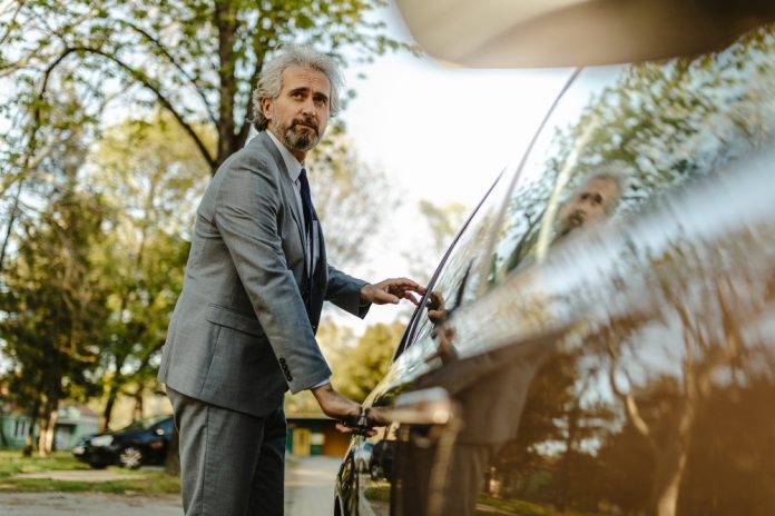 A handsome mature businessman getting in to a car.