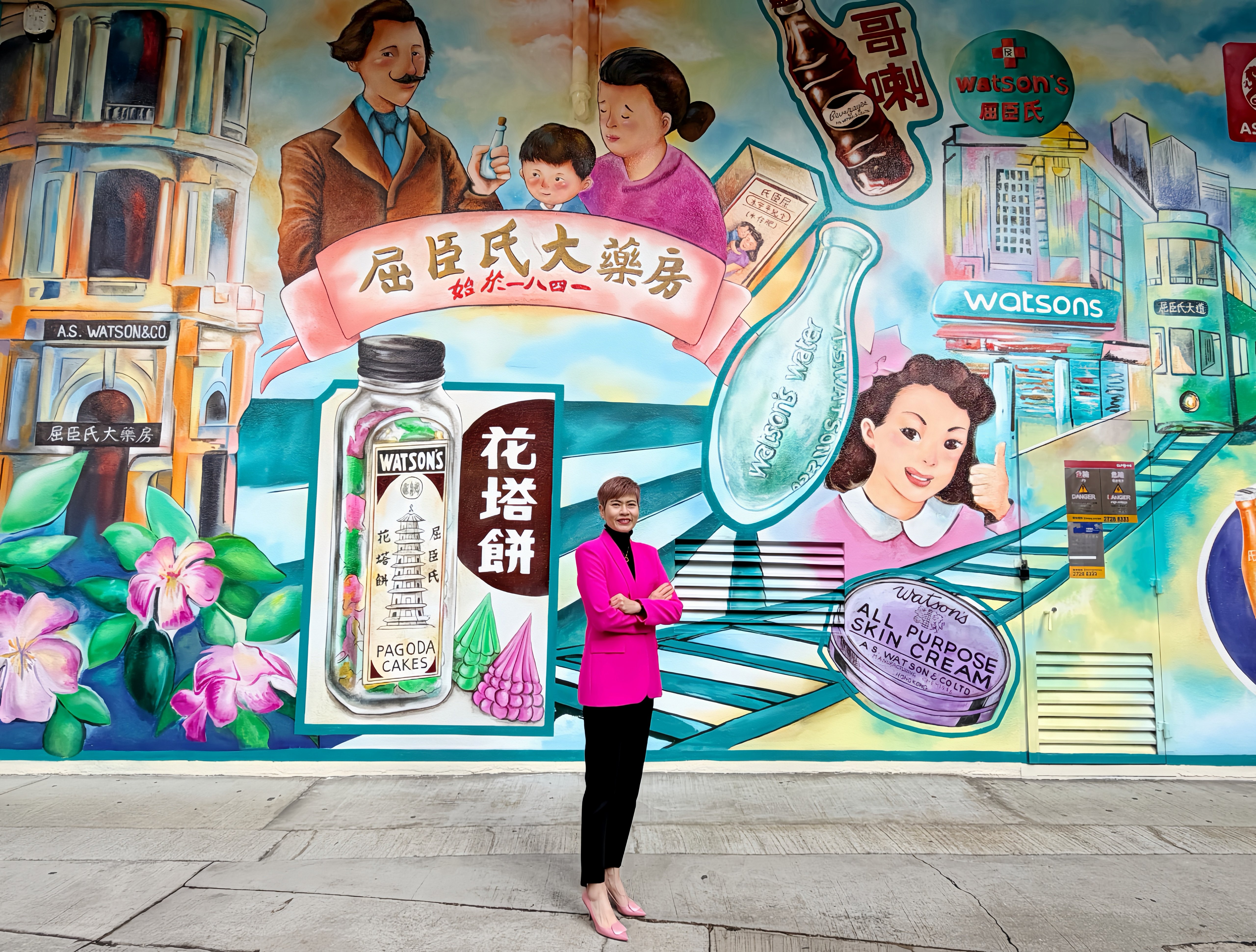 AS Watson Group CEO Dr Malina Ngai stands in front of a 6-meter-tall mural depicting the company's evolution from a single store in Hong Kong to a global health and beauty retailer, as the Group marks its 185th anniversary.